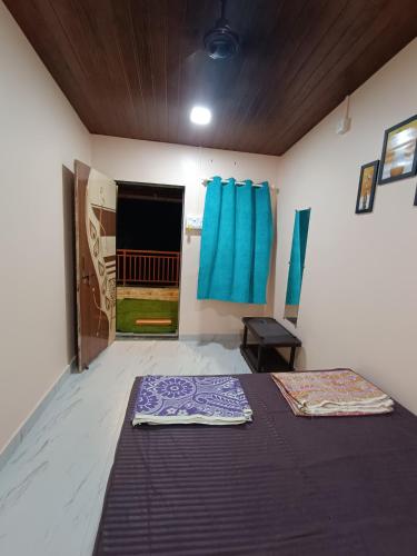 a room with a bed and a window with blue curtains at Aagman Homestay in Srīvardhan