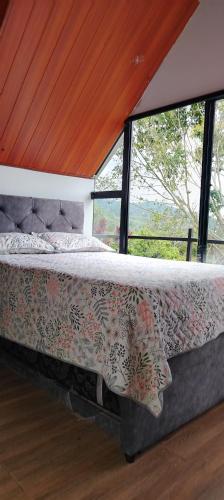 a bed in a room with a large window at Cabaña jacuzi interno in El Chocho
