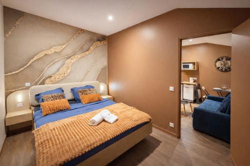 a bedroom with a large bed and a blue couch at Le Saphir avec Parking gratuit in Montigny-le-Bretonneux