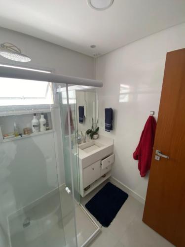 a bathroom with a glass shower and a sink at Quarto próx a Praia do Morro in Guarapari