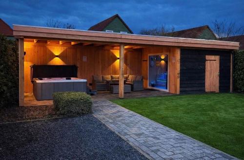 a pavilion with a hot tub in a backyard at Wellness huis voor 6 personen aan het strand 'Zeeuwse Rust' in Wemeldinge