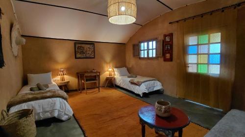 a bedroom with two beds and a table in a room at Les Jardins de Taja in Ourika