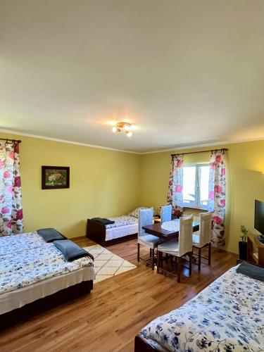 a room with three beds and a table and chairs at Pod Modrzewiem in Pogorzelce