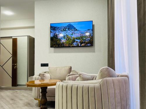 a living room with a couch and a tv on the wall at Royal Renaissance Boutique by IGIT in Yerevan