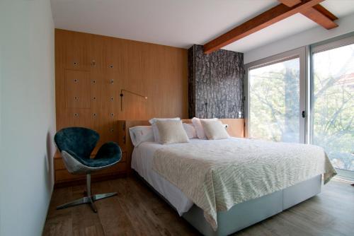 a bedroom with a bed and a chair and a window at Cal Tonarro in Organyà