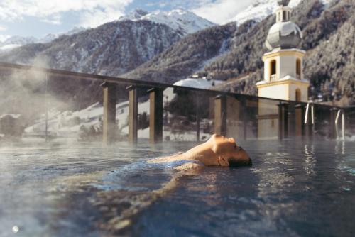 a man laying in the water in a bath tub at Hotel Kirchenwirt in Kaunertal
