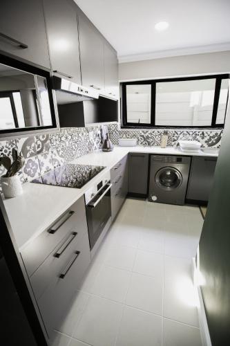 a kitchen with white counters and a washer and dryer at Wave Inn Guesthouse in Valsbaai