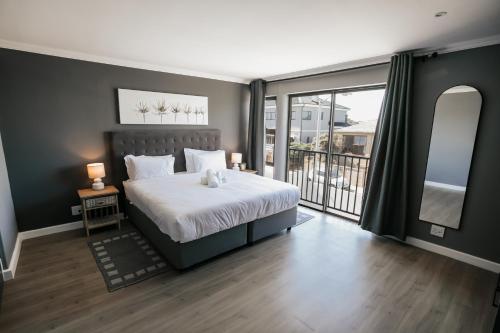 a bedroom with a bed and a large window at Wave Inn Guesthouse in Valsbaai