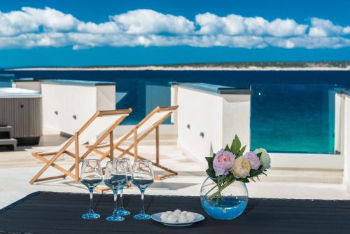 a table with three wine glasses and a vase with flowers at Luxury Mandre Penthouse in Mandre