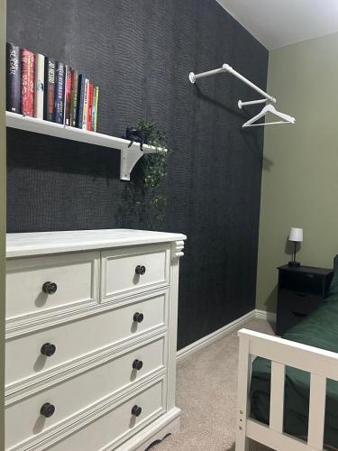 a bedroom with a white dresser and a black wall at Entire 3 bedroom deluxe house in Cleckheaton