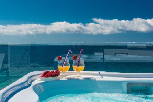 two glasses of wine and fruit in a swimming pool at Luxury Mandre Penthouse in Mandre