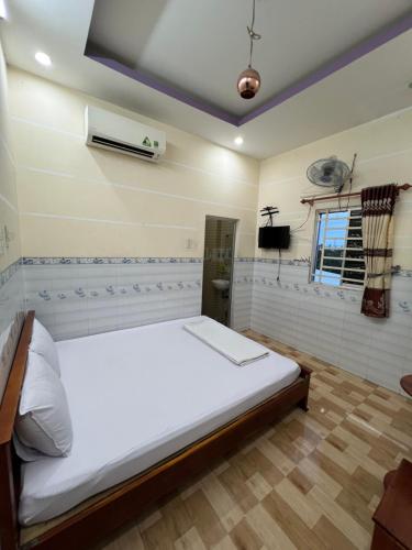 a bedroom with a large white bed and a window at Nhà nghỉ Phú Mỹ in Ấp An Mỹ