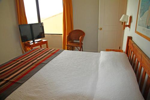 a bedroom with a bed with a television and a chair at Club Playa Blanca in Playa Blanca