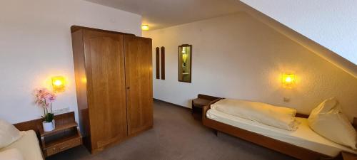 a small room with a bed and a cabinet at Pension Hauber - Hotzenwaldblick in Herrischried
