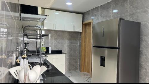 a kitchen with a stainless steel refrigerator and white cabinets at Luxury 3Bedroom Apartment in Sangotedo Ajah in Lekki