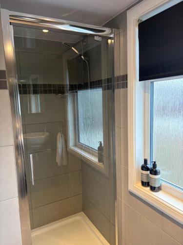a glass shower in a bathroom with a window at Waterside House B&B in Ullapool