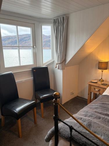a bedroom with two chairs and a bed and windows at Waterside House B&B in Ullapool