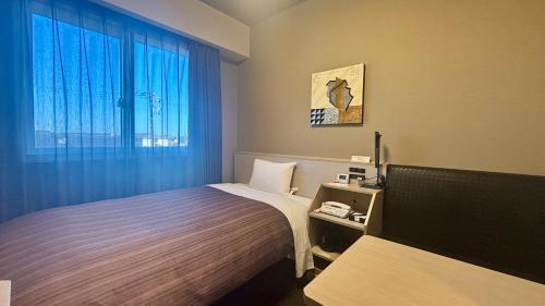 a hotel room with a bed and a window at Hotel Route-Inn Natori Iwanuma Inter -Sendai Kuko- in Natori
