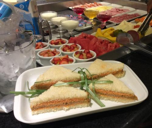 a table with a plate of sandwiches and bowls of food at Mara Turismo Hotel in Catalão