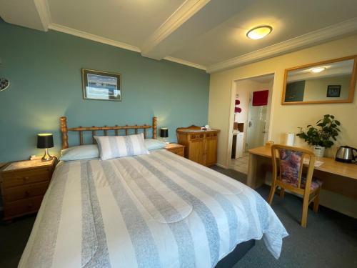 a bedroom with a large bed with a desk and a desk at Citrus Grove in Nelson