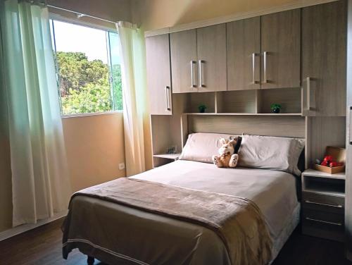 a teddy bear sitting on a bed in a bedroom at Casa da Colina Curitiba com piscina in Curitiba