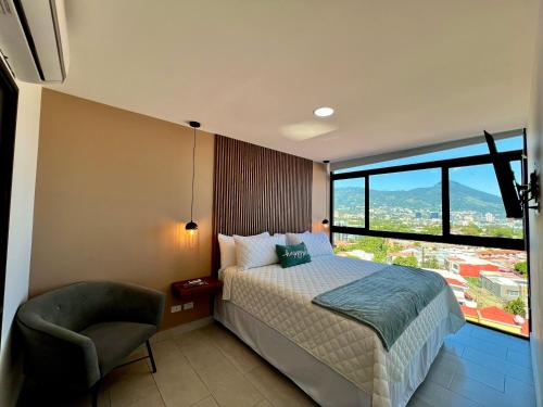 a bedroom with a bed and a chair and a window at Avitat Link in San Salvador