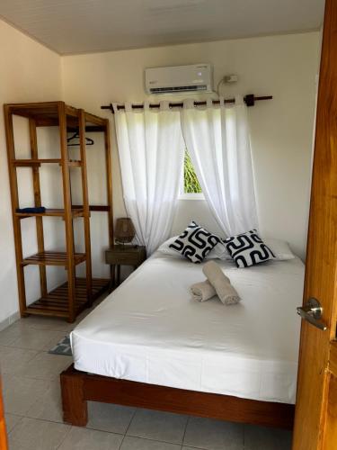 a bedroom with a bed with white curtains and a window at Entre Palmas Venao in Playa Venao