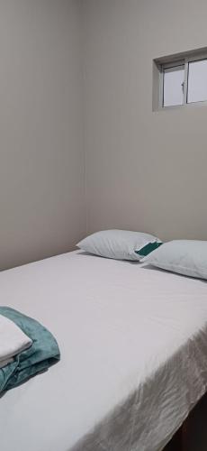a white bed with white sheets and a window at Hotel villa in Montería