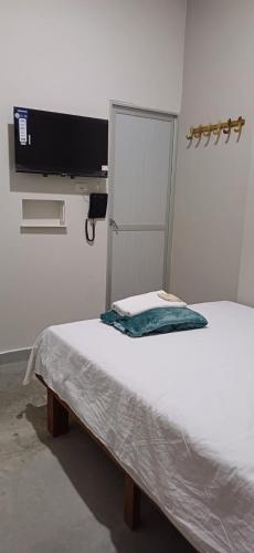 a bed in a room with a tv on the wall at Hotel villa in Montería
