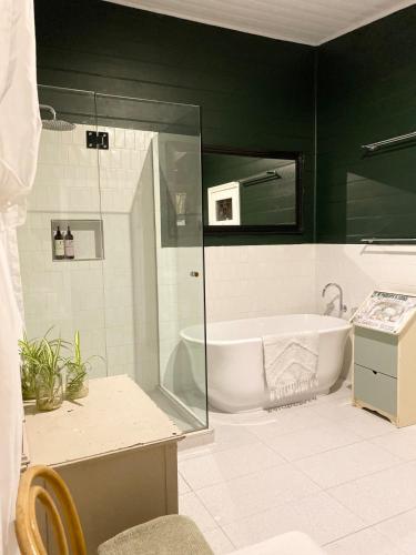 a bathroom with a tub and a glass shower at Korumburra Farmhouse in Korumburra
