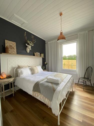 a bedroom with a large bed and a window at Korumburra Farmhouse in Korumburra