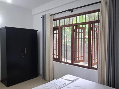 a bedroom with a black cabinet and a window at Layans Properties in Gampaha