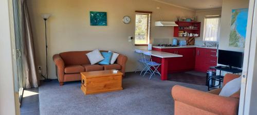 a living room with a couch and a table and a kitchen at Cedar Cottage in Takaka