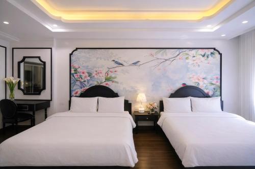 two beds in a room with a painting on the wall at Stella De Boutique Hotel in Sapa