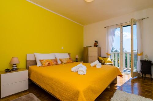 a yellow bedroom with a bed with towels on it at Villa La Vagabonda in Orasac