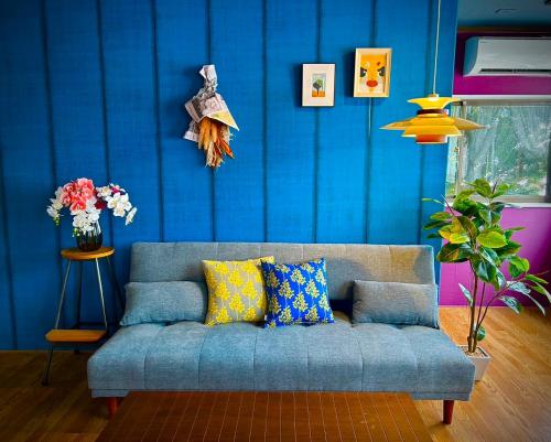 a blue living room with a couch with colorful pillows at 別邸錦ヶ丘パークヒルズ in Kumamoto