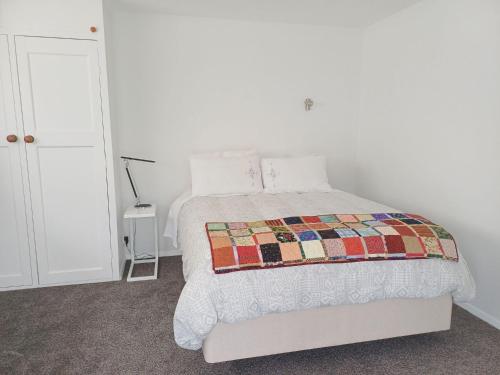 a bedroom with a bed with a quilt on it at Marigold in Manurewa in Auckland