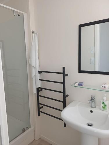 a bathroom with a sink and a shower and a mirror at Marigold in Manurewa in Auckland