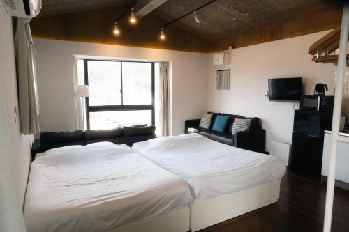 a bedroom with a large white bed and a window at Ashinoko Port Villa MIRAHAKONE in Hakone
