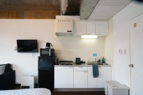 a kitchen with white cabinets and a black refrigerator at Ashinoko Port Villa MIRAHAKONE in Hakone
