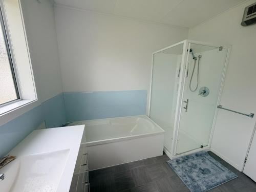 a white bathroom with a shower and a sink at Sunny Spacious Room, Free Parking, Close to Ferry in Wellington