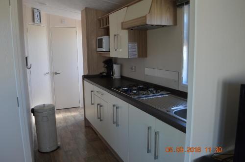 a kitchen with white cabinets and a black counter top at Vakantie Chalet Makkum in Makkum
