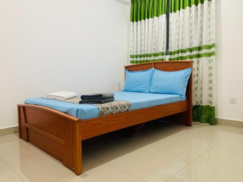 a wooden bed with blue sheets and a curtain at Urban View by CityScape in Colombo