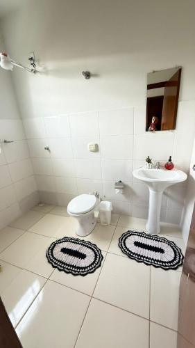 a white bathroom with a sink and a toilet at Canastra House in Delfinópolis