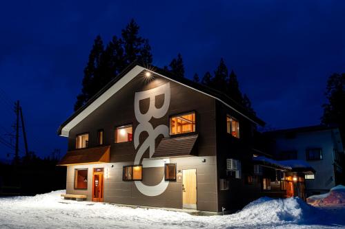 a house with a sign on the side of it in the snow at B and D HAKUBA IWATAKE in Hakuba