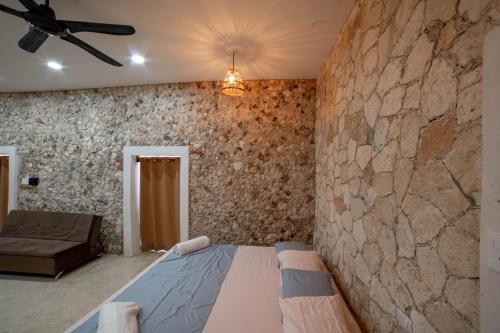 a bedroom with a stone wall and a bed at Villa Carulio in Ebtún