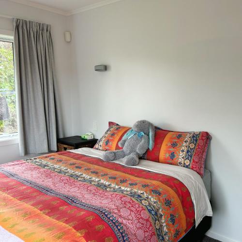 a stuffed teddy bear sitting on top of a bed at Sunny Spacious Room, Free Parking, Close to Ferry in Wellington