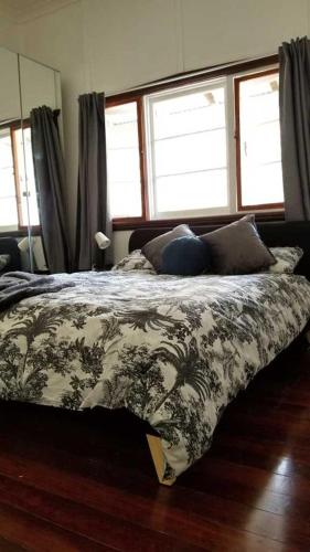 a bedroom with a bed with a comforter and two windows at Forest Edge Cottage Dwellingup in Dwellingup