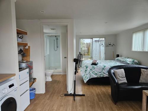 a bedroom with a bed and a couch and a chair at a private and sunny unit in the middle of north shore in Auckland
