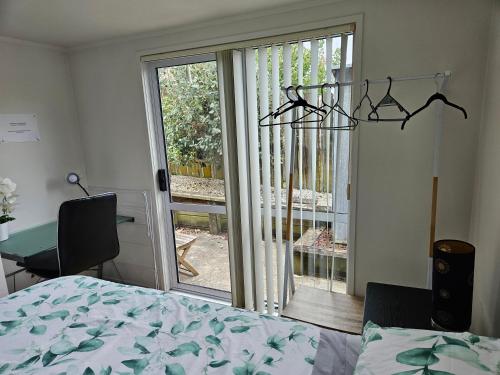 a bedroom with a bed and a sliding glass door at a private and sunny unit in the middle of north shore in Auckland